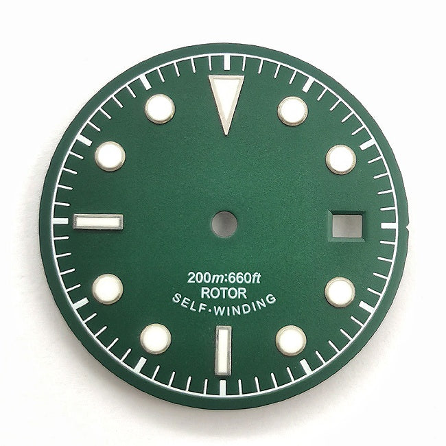 Green and white vintage-style diving watch dial with baton and dot markers.